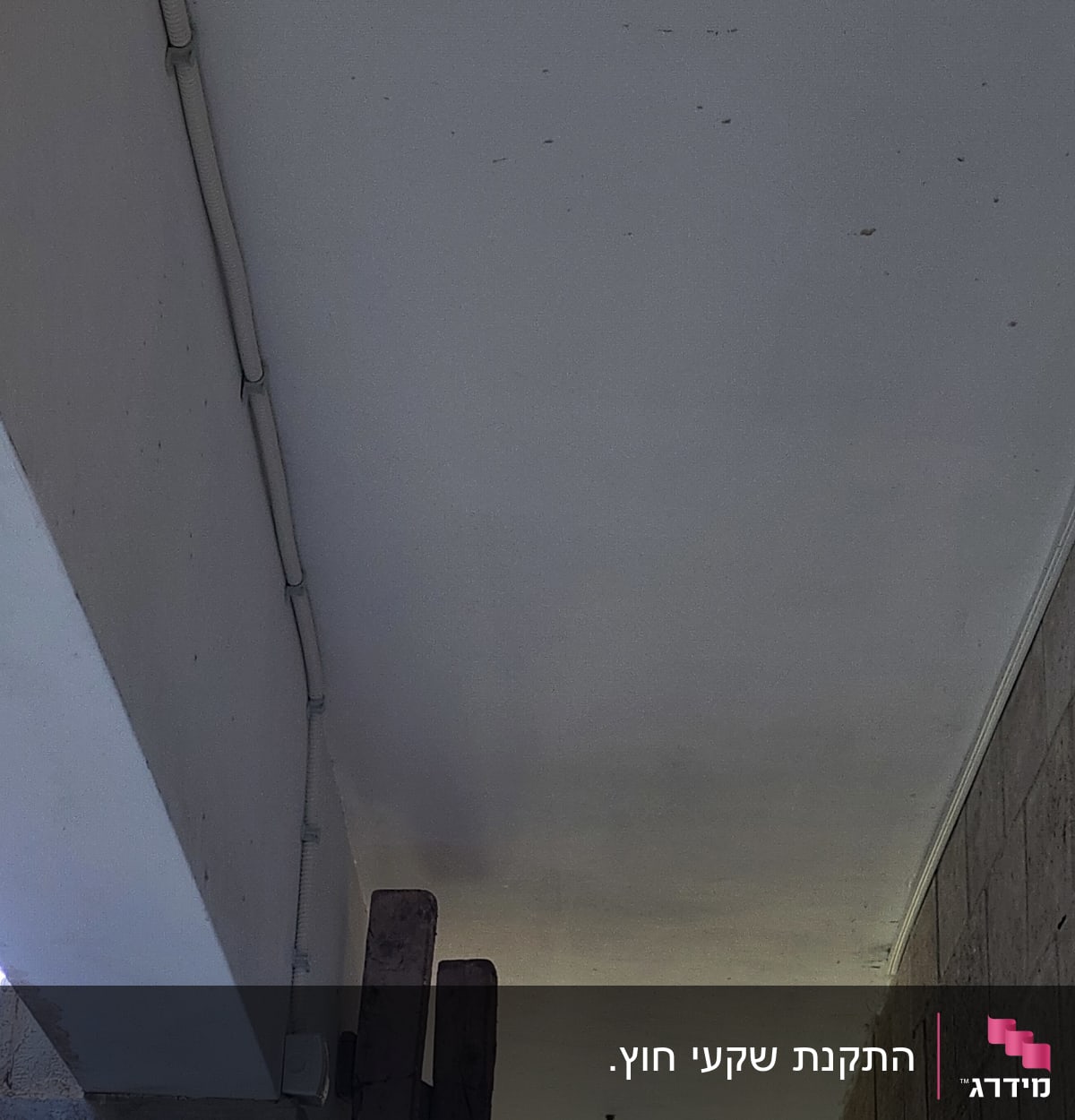 צינור חשמל לבן מותקן על תקרה לבנה